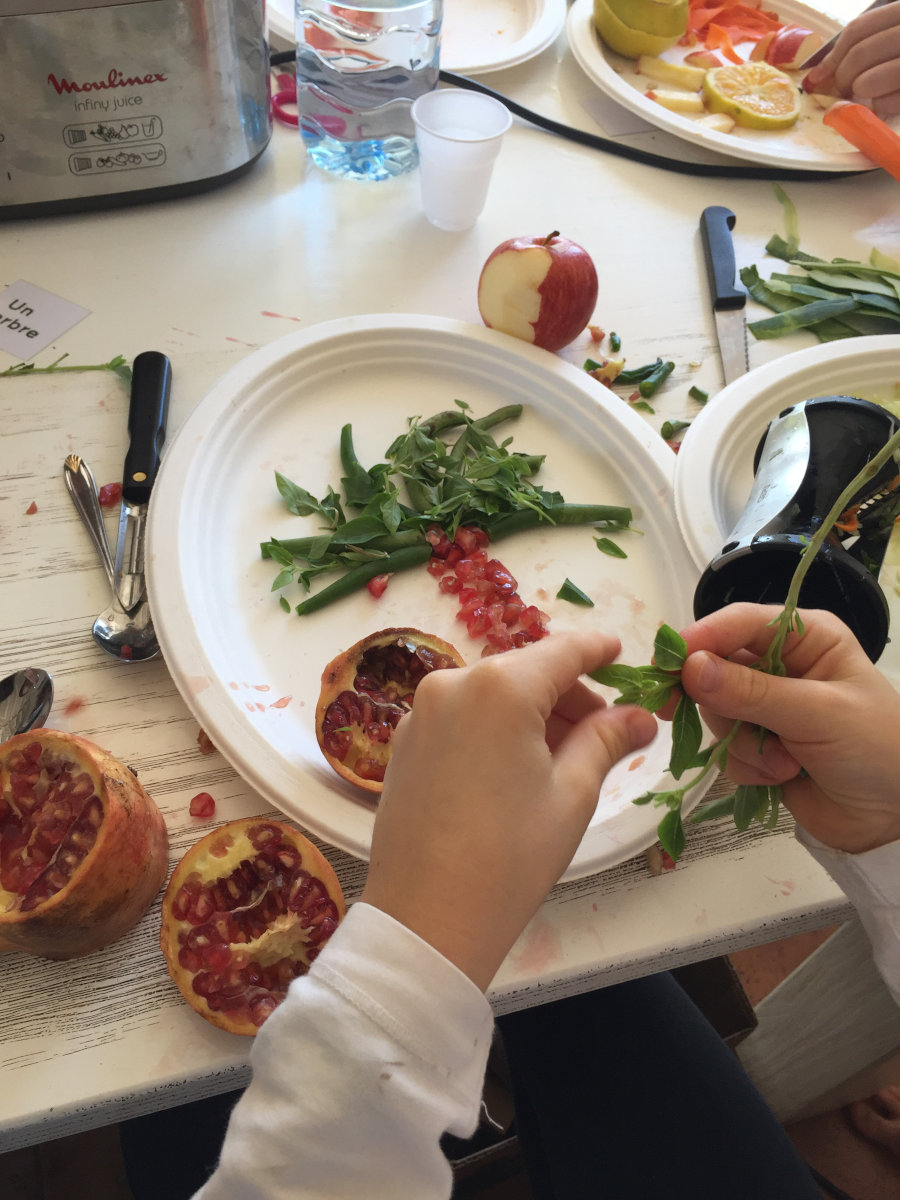 des petites mains qui créent un palmier en pépins de grenade et haricots verts